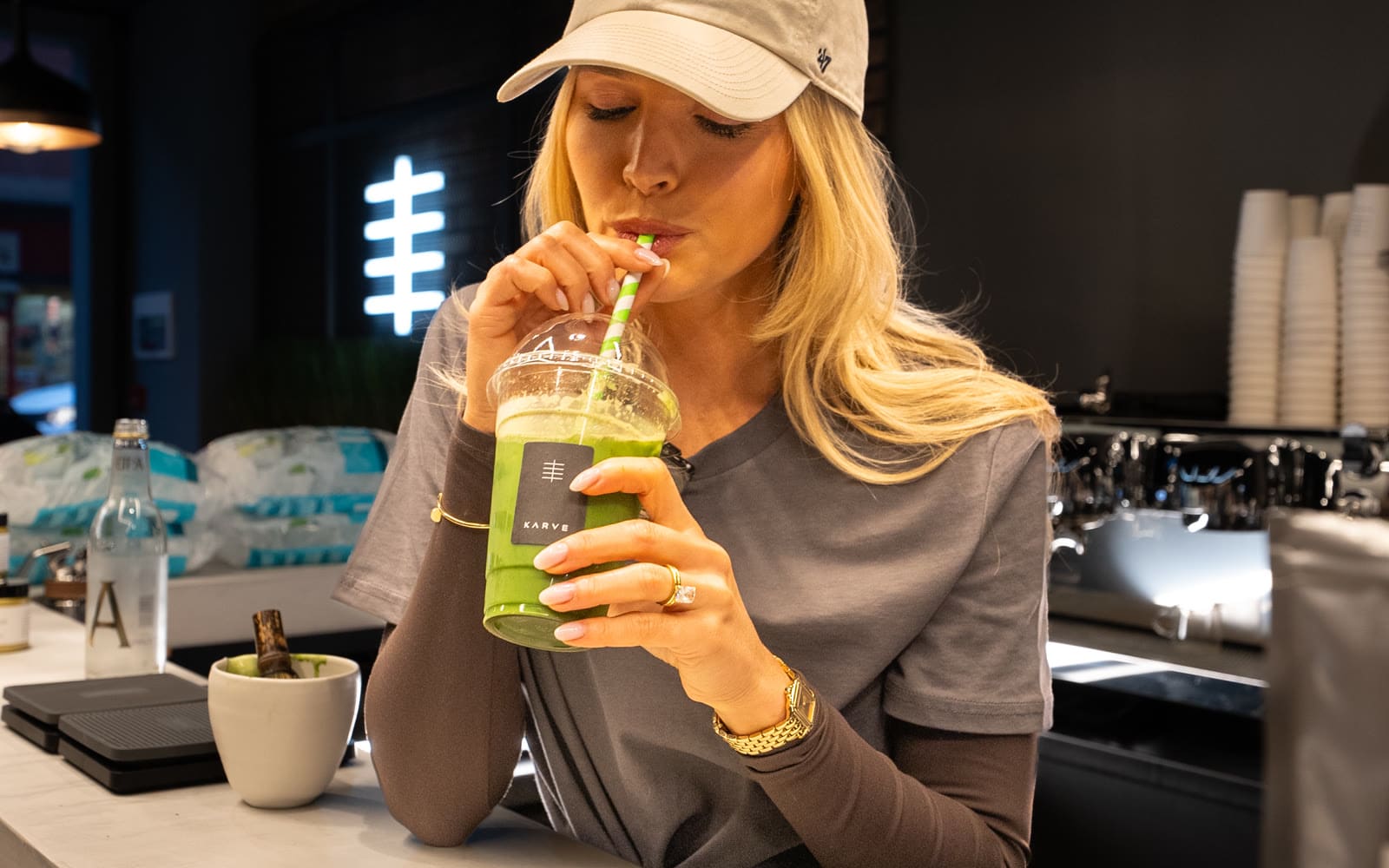 A guest sipping an iced matcha in a KARVE cup at the KARVE Café counter A guest sipping an iced matcha in a KARVE cup at the KARVE Café counter